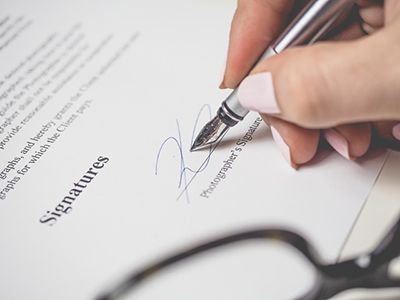 a woman's hand signing a certificate of liability